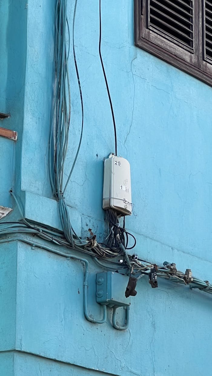 Close-up of a blue wall in an urban setting with electrical wiring and junction box.
